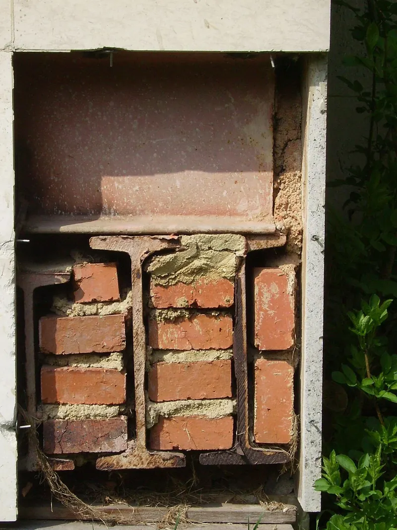 Old brickwork resting on a steel beam set into the wall as temporary support